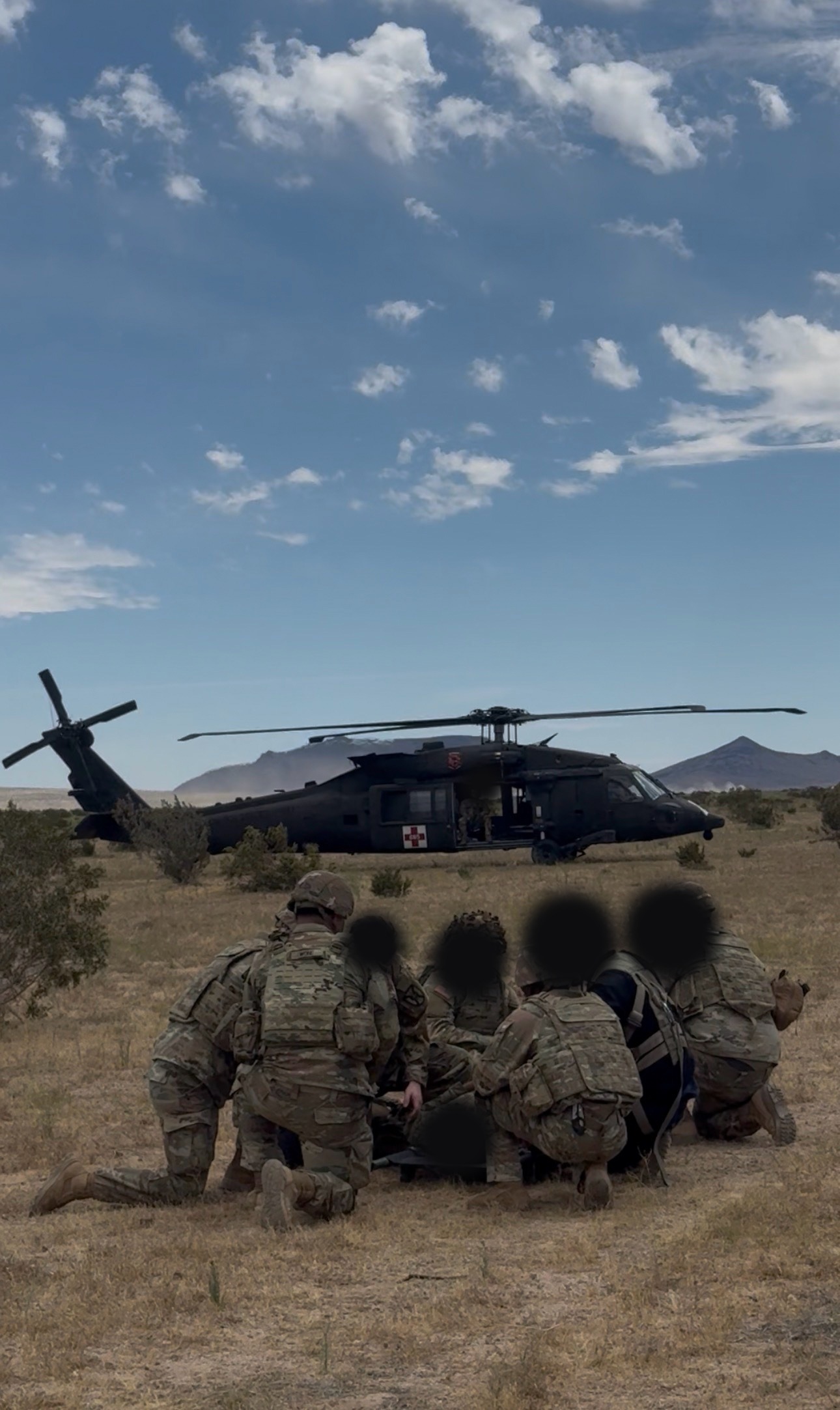 Soldiers training around a medical evacuation helicopter during a field exercise